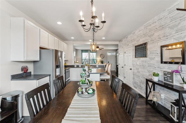 dining area with ceiling fan with notable chandelier, dark wood-type flooring, recessed lighting, and an accent wall