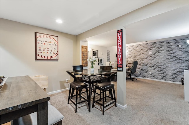 carpeted dining area with recessed lighting, brick wall, and baseboards