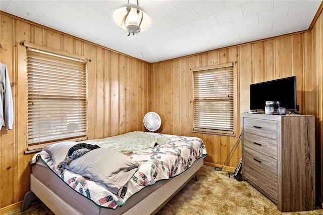 bedroom featuring multiple windows, light carpet, and wooden walls