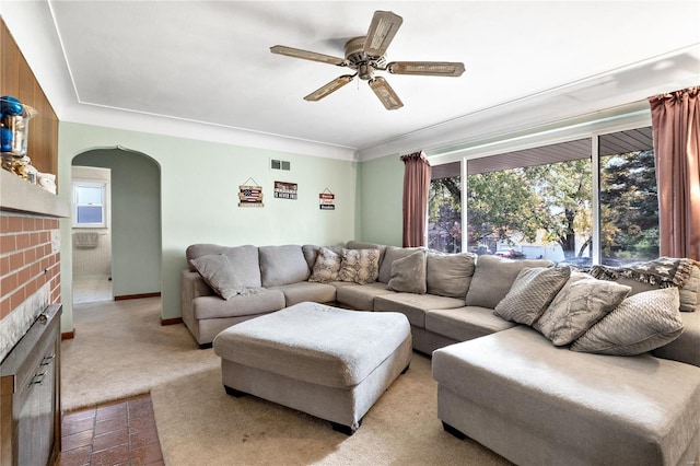 living room featuring a fireplace, light colored carpet, and ceiling fan