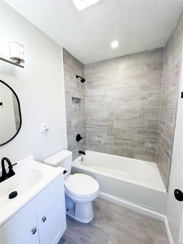 full bathroom featuring tiled shower / bath combo, vanity, a textured ceiling, and toilet