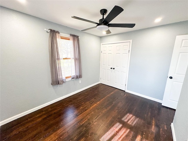 unfurnished bedroom with dark wood-type flooring, a closet, and ceiling fan