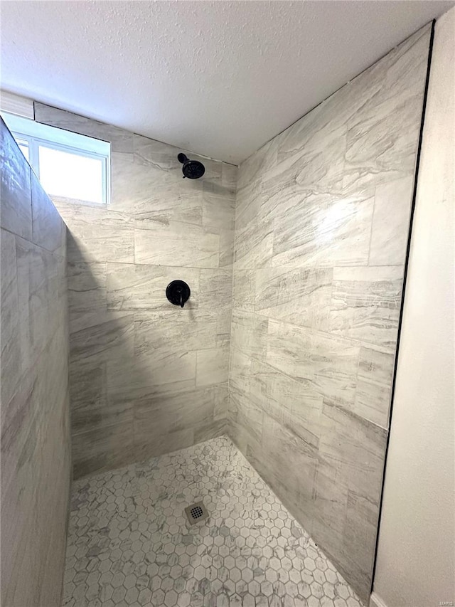 bathroom with a textured ceiling and a tile shower