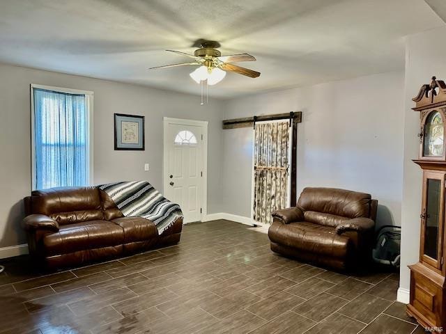 living room with a barn door, a wealth of natural light, and ceiling fan