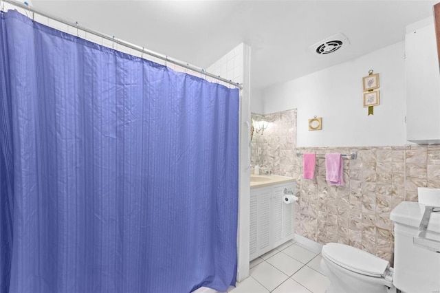 bathroom with toilet, vanity, tile walls, and tile patterned floors