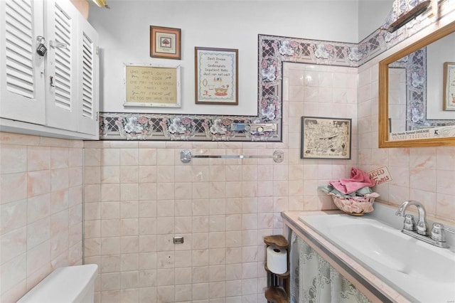 bathroom featuring sink, tile walls, and toilet