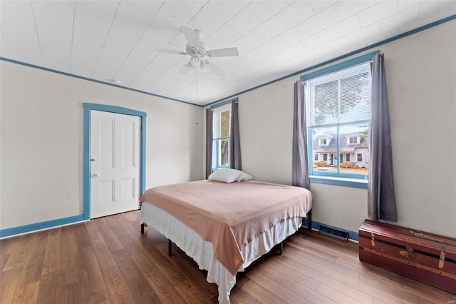 bedroom featuring hardwood / wood-style floors, ceiling fan, and crown molding