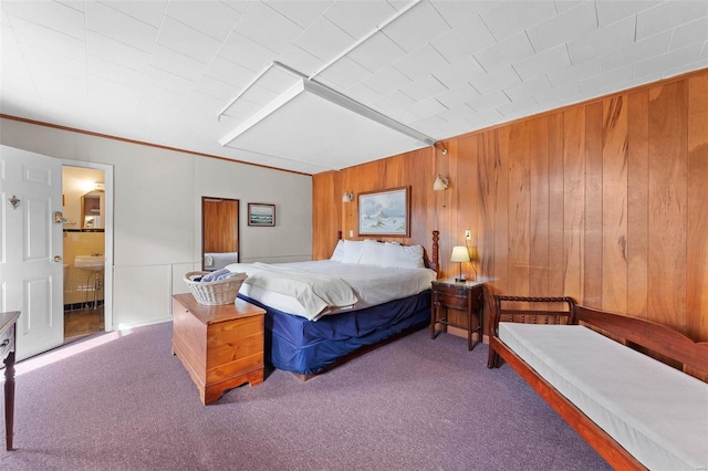 carpeted bedroom featuring wood walls and ensuite bathroom