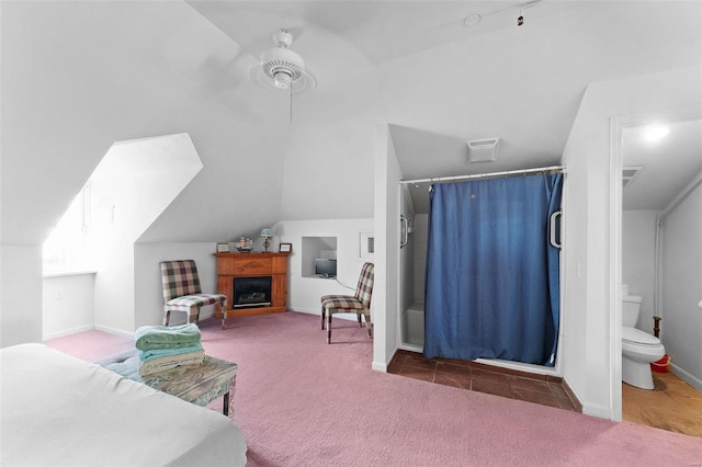 bedroom featuring vaulted ceiling, dark colored carpet, ceiling fan, and ensuite bath