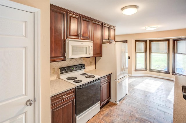 kitchen featuring decorative backsplash, light stone counters, and white appliances