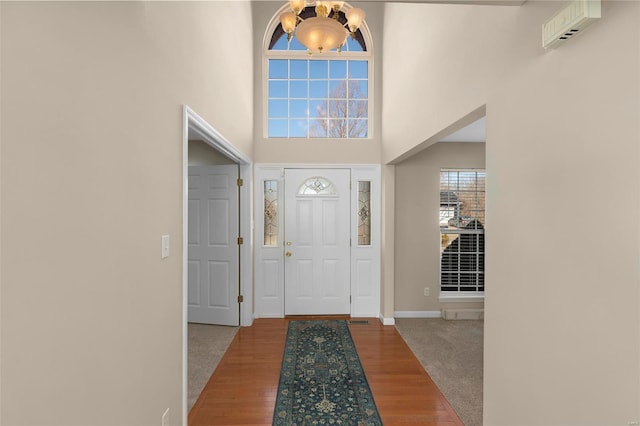 foyer entrance featuring hardwood / wood-style flooring, a chandelier, and a high ceiling