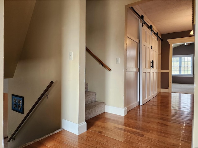 stairs with wood-type flooring and a barn door