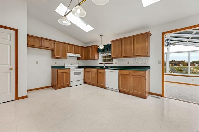 kitchen with lofted ceiling with skylight, sink, hanging light fixtures, and white appliances