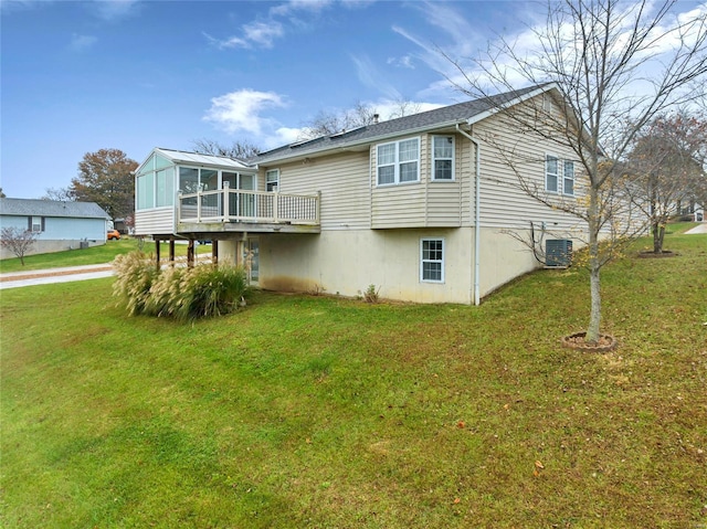 rear view of property featuring a yard, a sunroom, and a deck