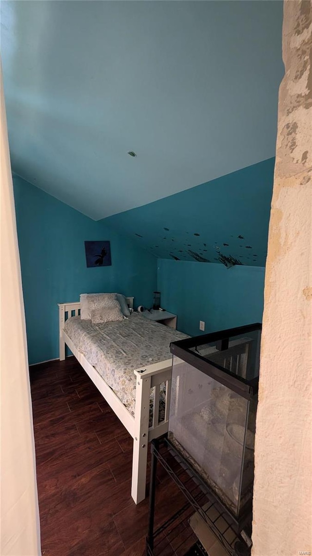 bedroom with dark wood-type flooring and lofted ceiling