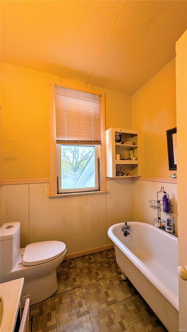 bathroom featuring a bathing tub, a textured ceiling, and toilet