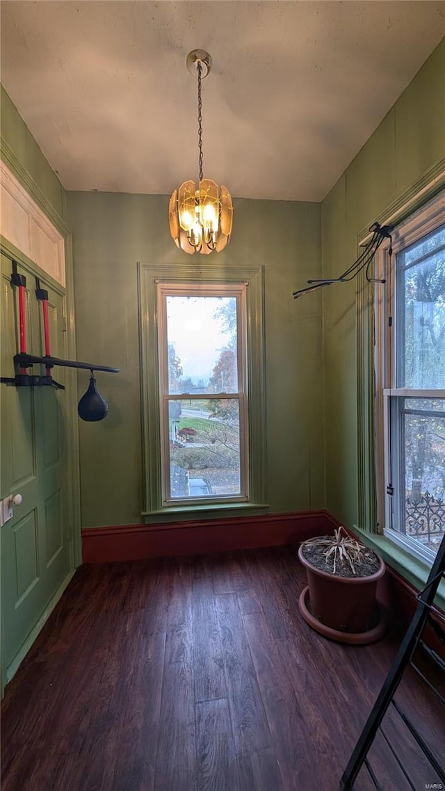 unfurnished dining area with dark hardwood / wood-style flooring and a notable chandelier