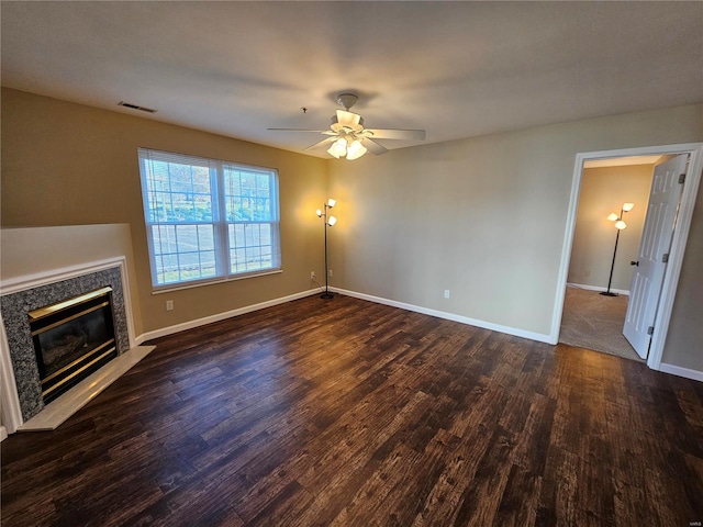 unfurnished living room with ceiling fan, dark wood-type flooring, and a premium fireplace