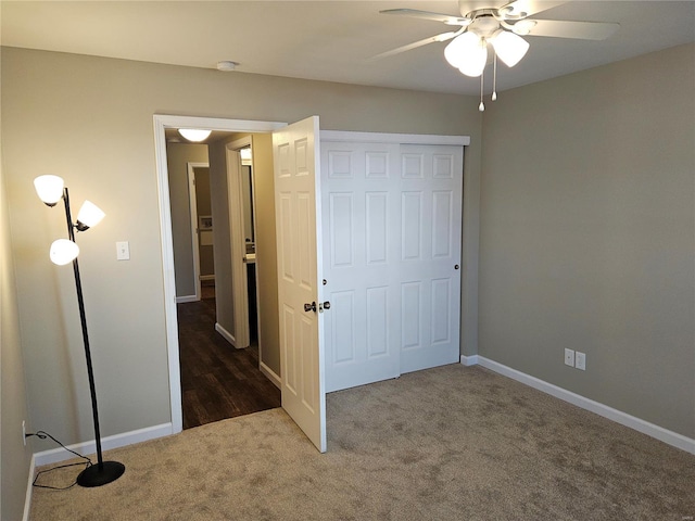 unfurnished bedroom with ceiling fan, a closet, and dark colored carpet