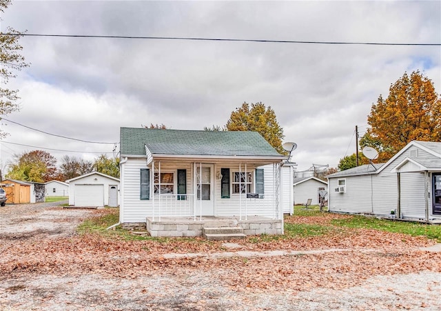 bungalow-style house with covered porch, a garage, and a storage shed