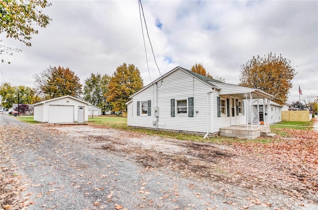 view of front of house with covered porch, a garage, and an outbuilding