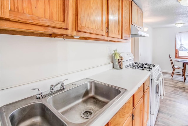 kitchen with white gas stove, a textured ceiling, sink, and light hardwood / wood-style floors