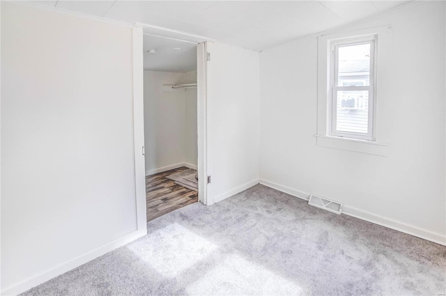 unfurnished bedroom with light colored carpet, a spacious closet, and a closet