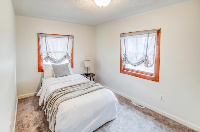 carpeted bedroom featuring multiple windows and a textured ceiling