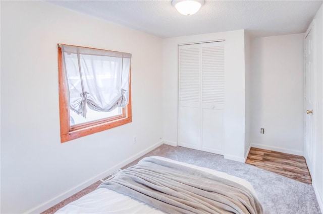 bedroom featuring hardwood / wood-style flooring, a textured ceiling, and a closet