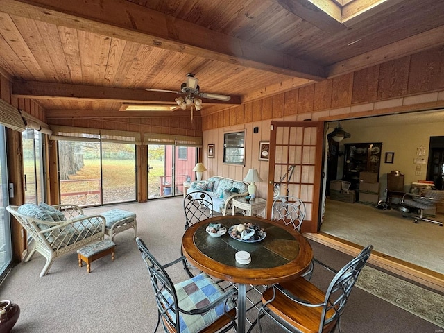 carpeted dining space with a skylight, beamed ceiling, ceiling fan, and wood ceiling