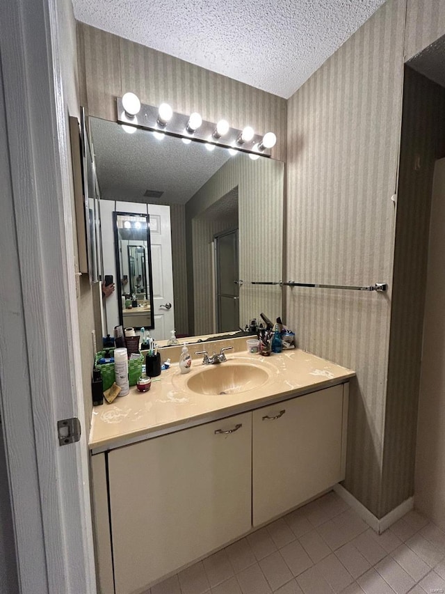 bathroom with tile patterned flooring, vanity, and a textured ceiling