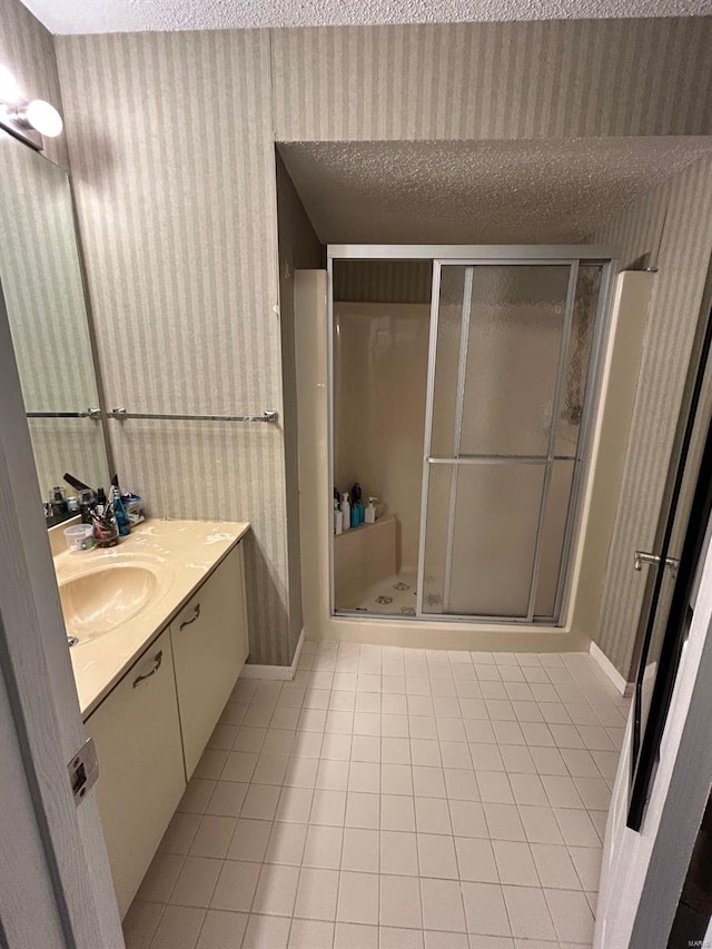 bathroom with tile patterned flooring, a textured ceiling, vanity, and an enclosed shower