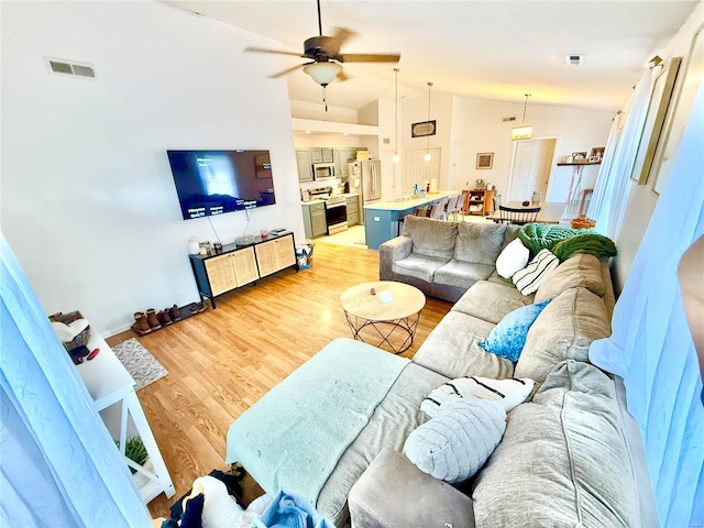 living room with hardwood / wood-style floors, vaulted ceiling, and ceiling fan