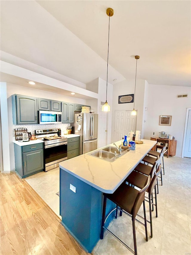 kitchen featuring tasteful backsplash, appliances with stainless steel finishes, hanging light fixtures, sink, and vaulted ceiling