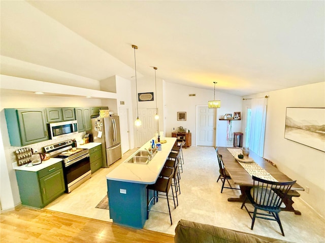 kitchen featuring appliances with stainless steel finishes, hanging light fixtures, light hardwood / wood-style floors, a breakfast bar area, and lofted ceiling