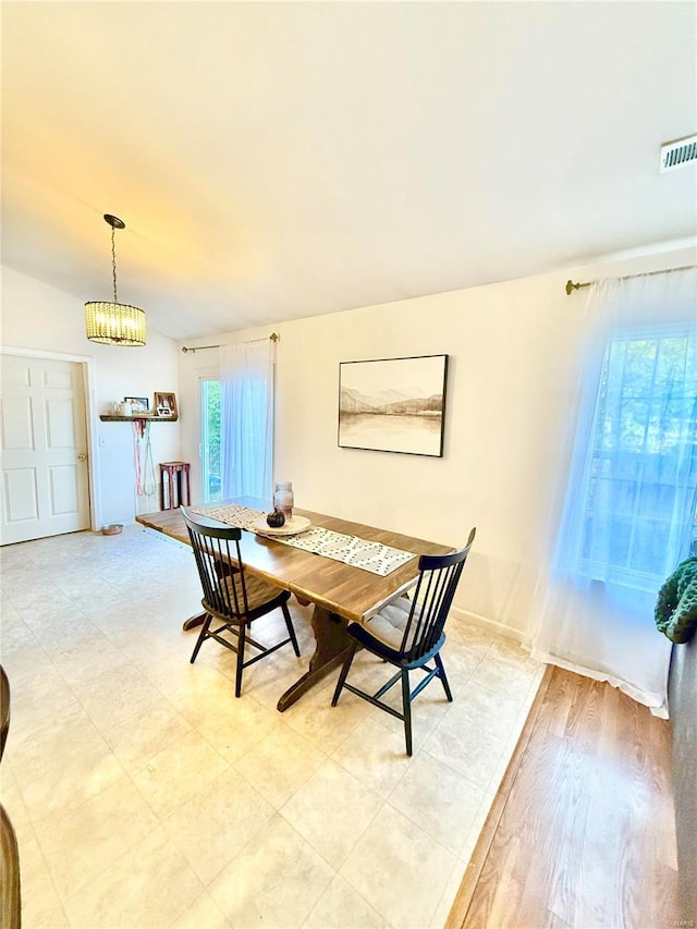 dining room with light hardwood / wood-style floors, vaulted ceiling, and an inviting chandelier