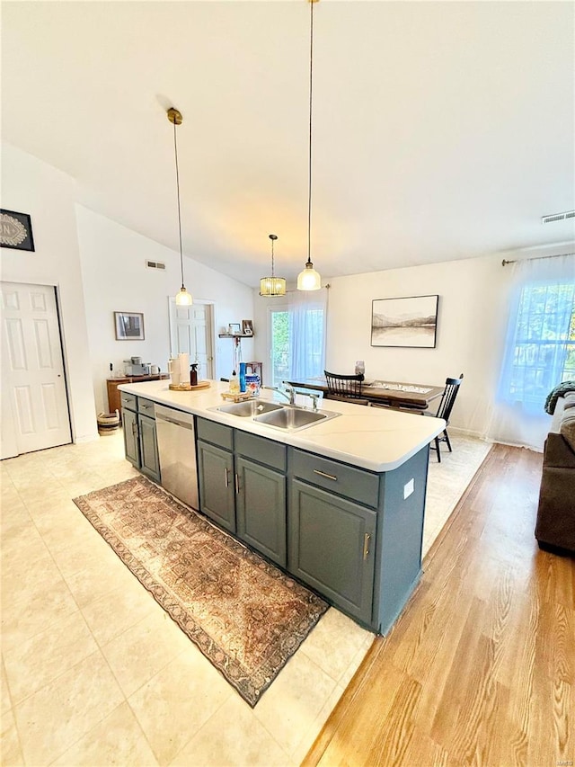 kitchen with dishwasher, a wealth of natural light, vaulted ceiling, and an island with sink