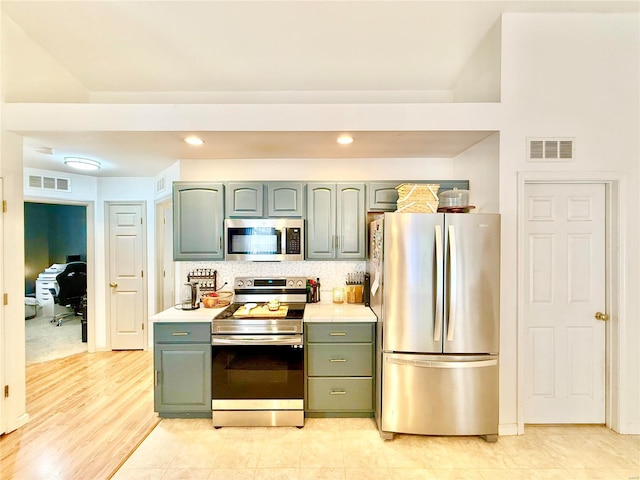 kitchen with decorative backsplash, appliances with stainless steel finishes, and light hardwood / wood-style floors