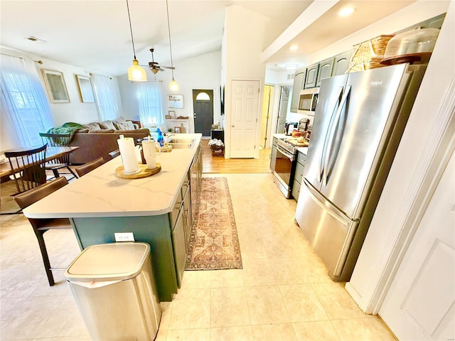 kitchen with lofted ceiling, a center island, hanging light fixtures, ceiling fan, and appliances with stainless steel finishes