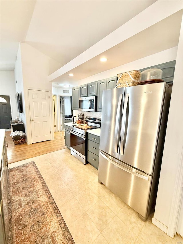 kitchen featuring gray cabinets, tasteful backsplash, appliances with stainless steel finishes, and light hardwood / wood-style floors