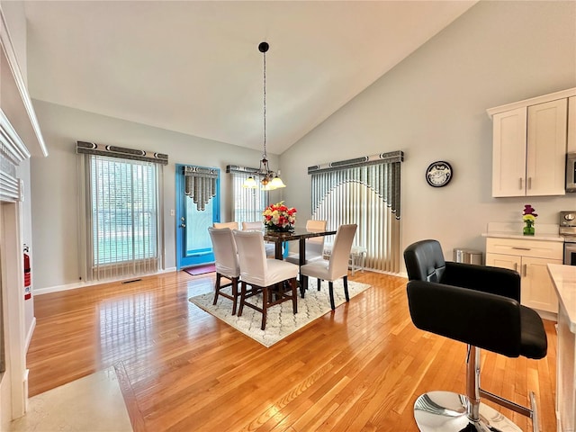 dining room featuring light wood-type flooring and high vaulted ceiling