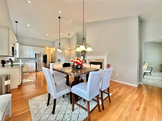 dining area with a towering ceiling and light hardwood / wood-style flooring