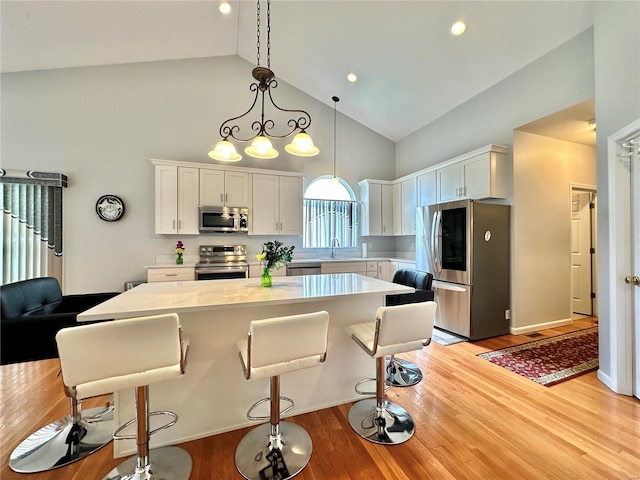 kitchen featuring white cabinets, high vaulted ceiling, stainless steel appliances, and light hardwood / wood-style floors