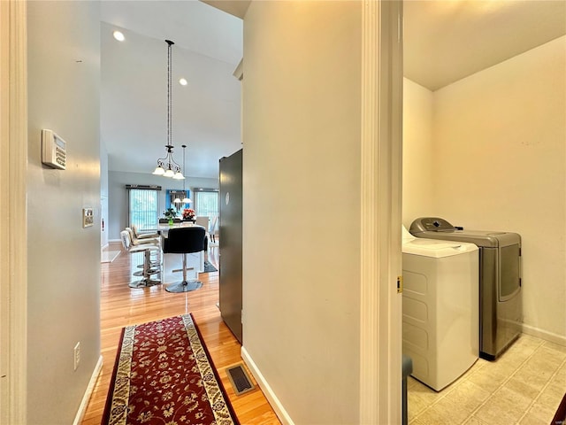 corridor with washer and clothes dryer, light wood-type flooring, and high vaulted ceiling