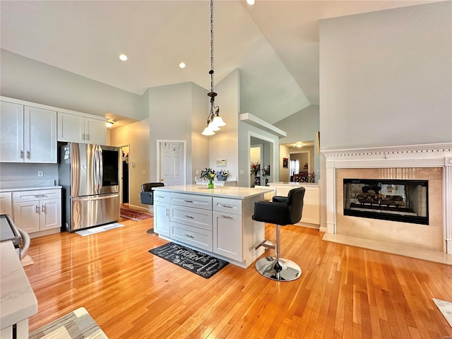 kitchen with stainless steel appliances, white cabinets, decorative light fixtures, and light wood-type flooring