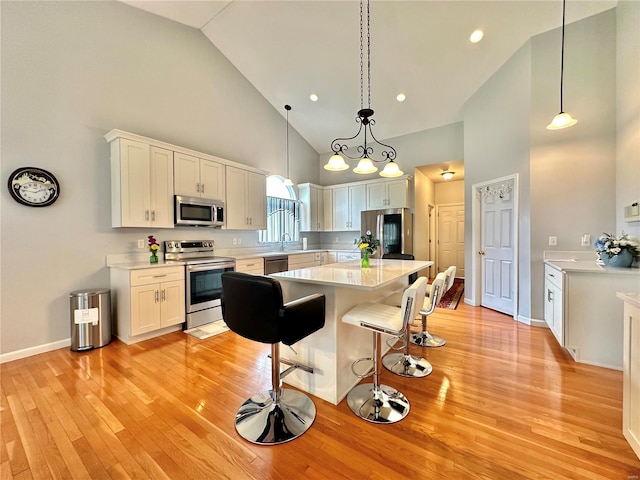 kitchen featuring high vaulted ceiling, white cabinetry, hanging light fixtures, and stainless steel appliances