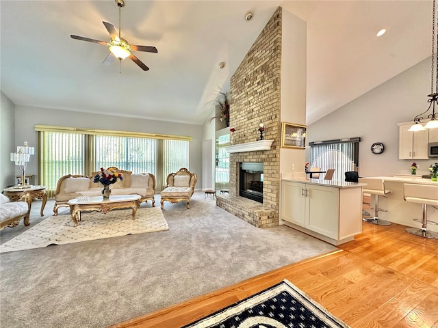 living room featuring a fireplace, ceiling fan, light hardwood / wood-style flooring, and high vaulted ceiling