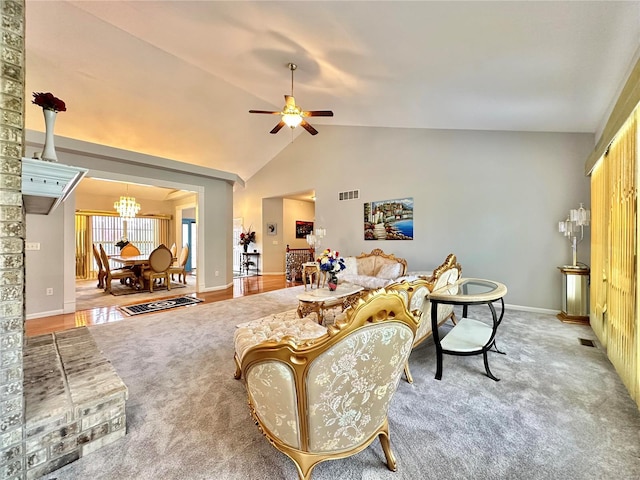 carpeted living room with ceiling fan with notable chandelier and high vaulted ceiling