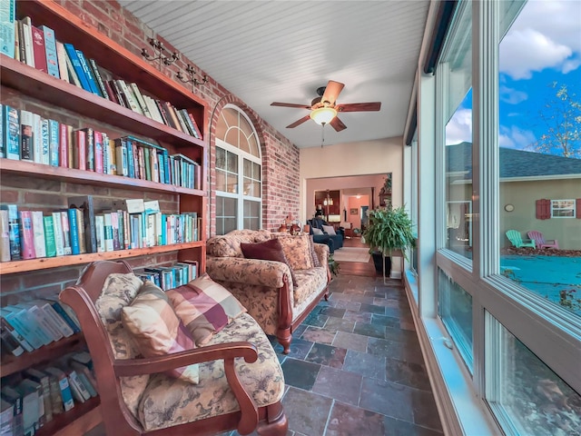 living area with brick wall and ceiling fan