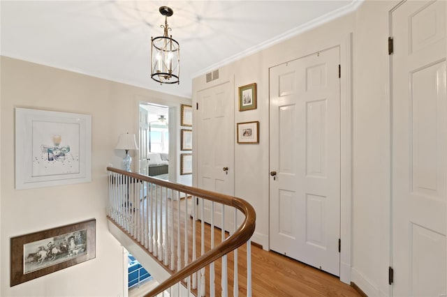 hallway with crown molding, light hardwood / wood-style floors, and a notable chandelier